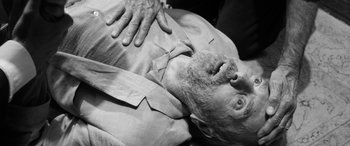 Movie still from “The Party” (2017), directed by Sally Potter – An older man is laying on his back; Close Up shot, Overhead angle