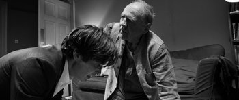 Movie still from “The Party” (2017), directed by Sally Potter – An older man and a younger man are looking at each other; Medium shot, Over the shoulder angle