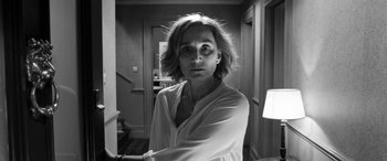 Movie still from “The Party” (2017), directed by Sally Potter – Black and white photograph of a woman in a white shirt; Medium shot, Low angle