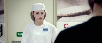 A woman wearing a chef's hat in front of a poster