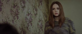 A woman with long red hair wearing a sweater