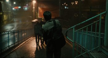 Movie still from “The Past” (2013), directed by Asghar Farhadi – A person with a backpack walking down a street; Wide shot, Over the shoulder angle