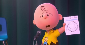 Movie still from “The Peanuts Movie” (2015), directed by Steve Martino – A charlie brown cartoon character holding up a piece of paper while standing next to a microphone; Medium shot, Over the shoulder angle