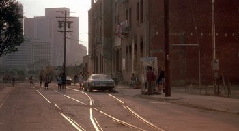 Movie still from “The People Under the Stairs” (1991), directed by Wes Craven – People are walking down the street in a city; Extreme Wide shot, High angle