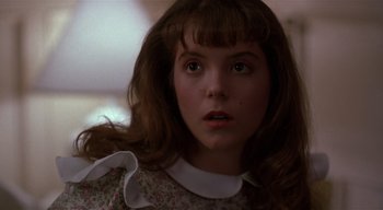 Movie still from “The People Under the Stairs” (1991), directed by Wes Craven – A young girl with a white collar and a pink dress; Close Up shot, Over the shoulder angle
