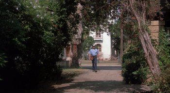 Movie still from “The People Under the Stairs” (1991), directed by Wes Craven – A man riding a skateboard down the middle of a street; Wide shot, Low angle