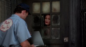 Movie still from “The People Under the Stairs” (1991), directed by Wes Craven – A man and a woman looking through a window; Medium shot, Over the shoulder angle