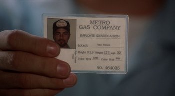 Movie still from “The People Under the Stairs” (1991), directed by Wes Craven – A person holding a metro gas company employee id card; Extreme Close Up shot, Overhead angle