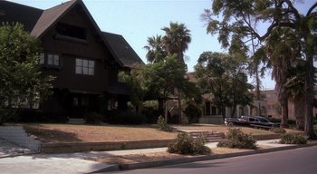 Movie still from “The People Under the Stairs” (1991), directed by Wes Craven – A street view of a house with a car parked on the side of the road; Wide shot, Low angle