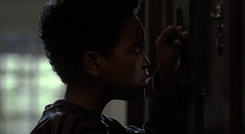 Movie still from “The People Under the Stairs” (1991), directed by Wes Craven – A young boy is painting a picture on a wall; Close Up shot, Low angle