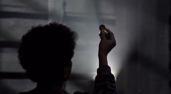 Movie still from “The People Under the Stairs” (1991), directed by Wes Craven – A person holding something up to the sky; Close Up shot, Over the shoulder angle