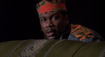 Movie still from “The People Under the Stairs” (1991), directed by Wes Craven – A man wearing a colorful hat looking at the camera; Close Up shot, Low angle