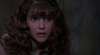 Movie still from “The People Under the Stairs” (1991), directed by Wes Craven – A young girl with brown curly hair looking at the camera; Close Up shot, Over the shoulder angle