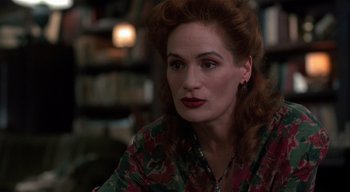 Movie still from “The People Under the Stairs” (1991), directed by Wes Craven – A woman sitting in a room with a book shelf in the background; Close Up shot, Over the shoulder angle