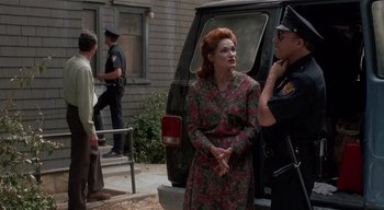 Movie still from “The People Under the Stairs” (1991), directed by Wes Craven – A woman in a floral dress talking to a police officer; Medium shot, Over the shoulder angle
