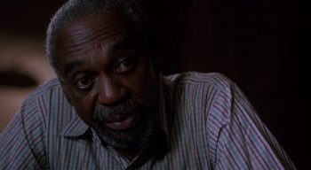 Movie still from “The People Under the Stairs” (1991), directed by Wes Craven – An older man is looking at the camera; Close Up shot, High angle