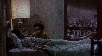 Movie still from “The People Under the Stairs” (1991), directed by Wes Craven – A young boy sitting on a bed next to an older person; Wide shot, High angle