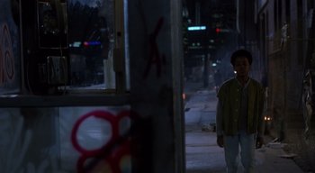 Movie still from “The People Under the Stairs” (1991), directed by Wes Craven – A man walking down a street at night; Wide shot, Over the shoulder angle