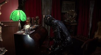 Movie still from “The People Under the Stairs” (1991), directed by Wes Craven – A man sitting at a dining room table; Medium shot, High angle