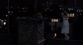 Movie still from “The People Under the Stairs” (1991), directed by Wes Craven – A man and a woman standing on top of a brick building; Wide shot, High angle