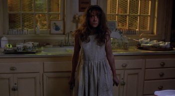 Movie still from “The People Under the Stairs” (1991), directed by Wes Craven – A woman standing in a kitchen holding a pair of scissors; Medium shot, Low angle