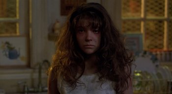 Movie still from “The People Under the Stairs” (1991), directed by Wes Craven – A young girl with long brown hair stares into the camera; Close Up shot, Over the shoulder angle