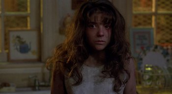 Movie still from “The People Under the Stairs” (1991), directed by Wes Craven – A young girl with long brown hair stares into the camera; Close Up shot, Over the shoulder angle