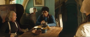 Movie still from “The Personal History of David Copperfield” (2019), directed by Armando Iannucci – A person sitting at a table with a bowl of food; Medium shot, Over the shoulder angle