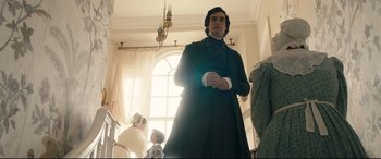 Movie still from “The Personal History of David Copperfield” (2019), directed by Armando Iannucci – A man standing in front of a window in a room; Medium shot, Low angle