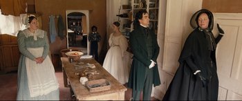 Movie still from “The Personal History of David Copperfield” (2019), directed by Armando Iannucci – A man and a woman standing in front of a table; Wide shot, High angle