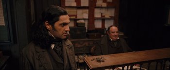 Movie still from “The Personal History of David Copperfield” (2019), directed by Armando Iannucci – Two men sitting at a table in a room; Medium shot, Over the shoulder angle