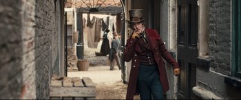 Movie still from “The Personal History of David Copperfield” (2019), directed by Armando Iannucci – A man wearing a top hat and a red coat; Medium shot, Over the shoulder angle