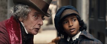 Movie still from “The Personal History of David Copperfield” (2019), directed by Armando Iannucci – A man and a boy wearing hats looking at each other; Close Up shot, Over the shoulder angle