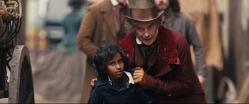 Movie still from “The Personal History of David Copperfield” (2019), directed by Armando Iannucci – A man and a boy in a hat and suit; Medium shot, Over the shoulder angle