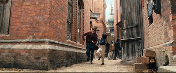 Movie still from “The Personal History of David Copperfield” (2019), directed by Armando Iannucci – A man and a boy running down a street; Wide shot, High angle