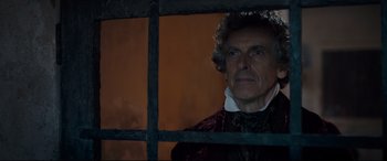 Movie still from “The Personal History of David Copperfield” (2019), directed by Armando Iannucci – An older man looking out of a jail cell window; Close Up shot, Over the shoulder angle