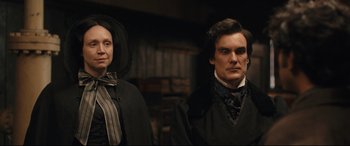 Movie still from “The Personal History of David Copperfield” (2019), directed by Armando Iannucci – A man and a woman standing next to each other; Medium shot, Over the shoulder angle