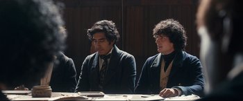 Movie still from “The Personal History of David Copperfield” (2019), directed by Armando Iannucci – A group of people sitting at a table; Medium shot, Over the shoulder angle