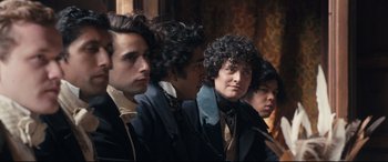 Movie still from “The Personal History of David Copperfield” (2019), directed by Armando Iannucci – A group of young men sitting next to each other; Medium shot, Over the shoulder angle