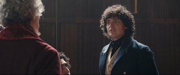 Movie still from “The Personal History of David Copperfield” (2019), directed by Armando Iannucci – A man in a suit and tie looking into a mirror; Medium shot, Over the shoulder angle