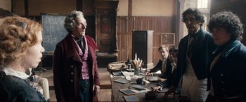 Movie still from “The Personal History of David Copperfield” (2019), directed by Armando Iannucci – A group of people sitting around a table; Medium shot, Low angle