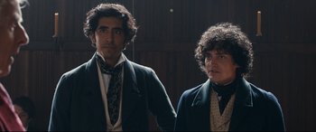 Movie still from “The Personal History of David Copperfield” (2019), directed by Armando Iannucci – Two men in suits and ties standing next to each other; Medium shot, Low angle