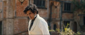 Movie still from “The Personal History of David Copperfield” (2019), directed by Armando Iannucci – A man in a white suit and a black tie; Medium shot, Over the shoulder angle