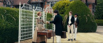 Movie still from “The Personal History of David Copperfield” (2019), directed by Armando Iannucci – A man and a woman are handing something to another man; Medium shot, Over the shoulder angle