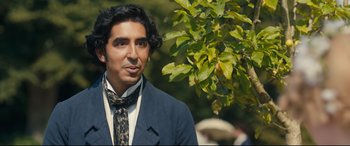 Movie still from “The Personal History of David Copperfield” (2019), directed by Armando Iannucci – A man in a suit and tie standing next to a tree; Close Up shot, Over the shoulder angle