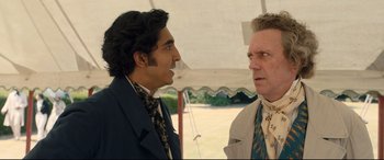 Movie still from “The Personal History of David Copperfield” (2019), directed by Armando Iannucci – Two men are standing next to each other; Medium shot, Over the shoulder angle