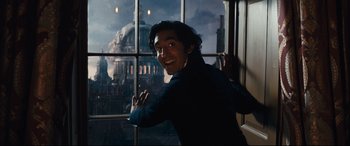 Movie still from “The Personal History of David Copperfield” (2019), directed by Armando Iannucci – A man standing in front of a window with a castle in the background; Medium shot, Low angle