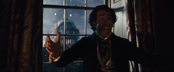 Movie still from “The Personal History of David Copperfield” (2019), directed by Armando Iannucci – A man in a suit and tie standing in front of a window; Medium shot, Low angle