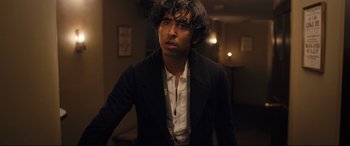 Movie still from “The Personal History of David Copperfield” (2019), directed by Armando Iannucci – A man in a black jacket is looking at the camera; Medium shot, Over the shoulder angle