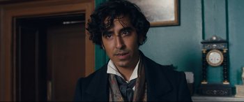 Movie still from “The Personal History of David Copperfield” (2019), directed by Armando Iannucci – A person wearing a suit and tie; Close Up shot, Over the shoulder angle